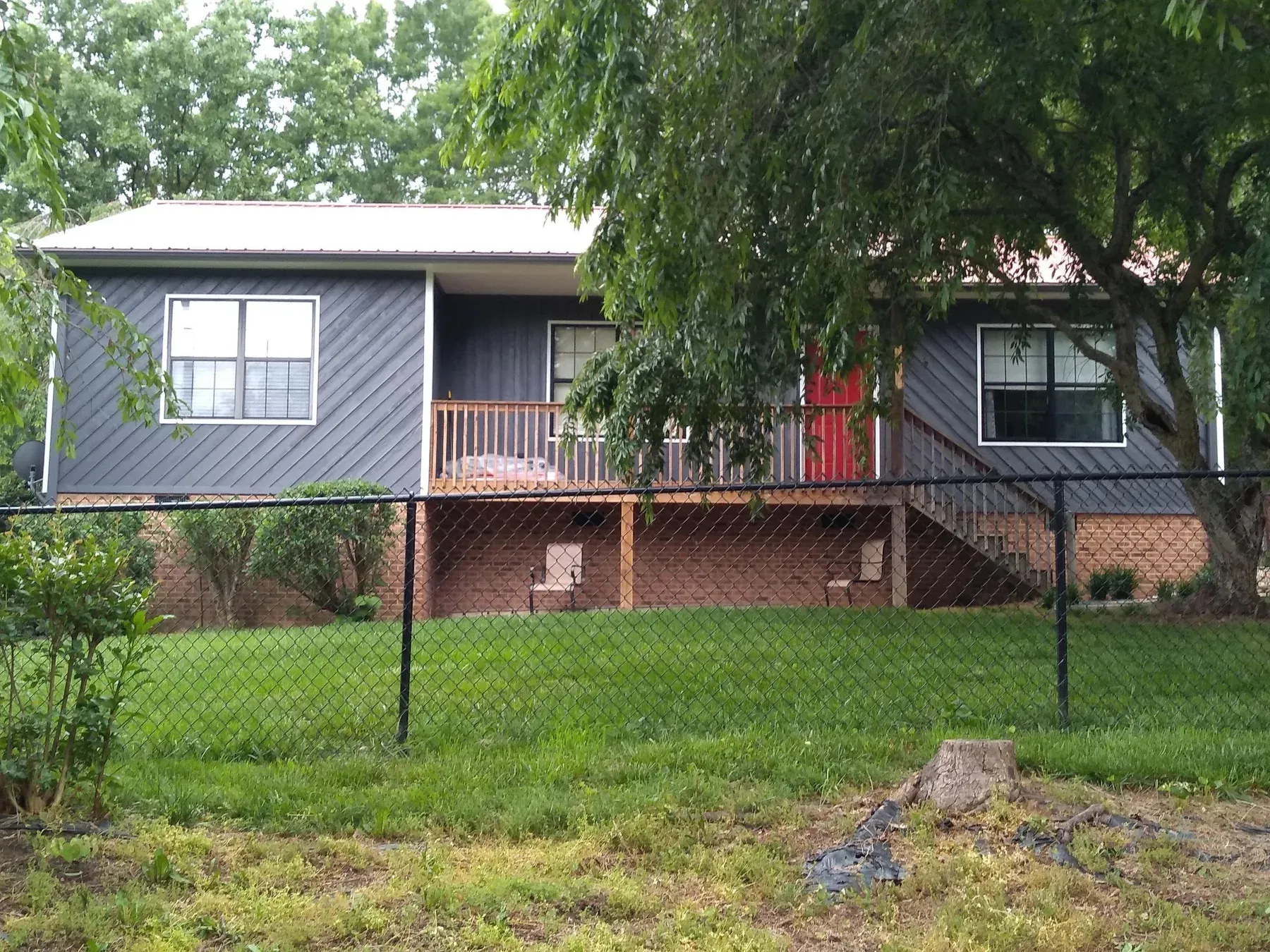 The same home after: slate blue-gray siding, white rails and a red front door
